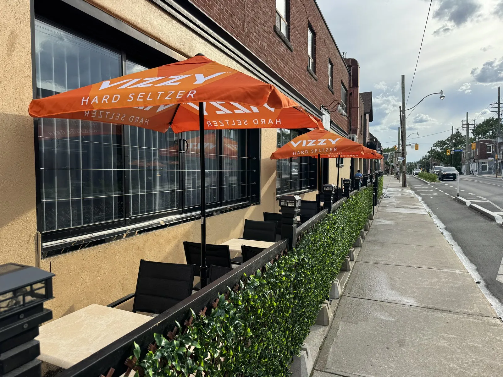 Looking down the Ace Restaurant patio with a row of orange umbrellas along Harbord Street