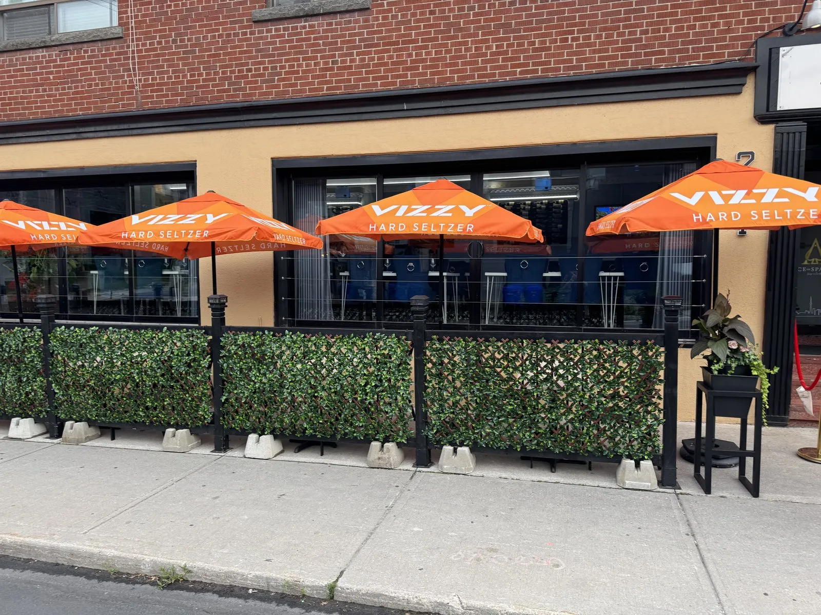 Patio seating behind a low hedge under matching umbrellas at Ace Restaurant
